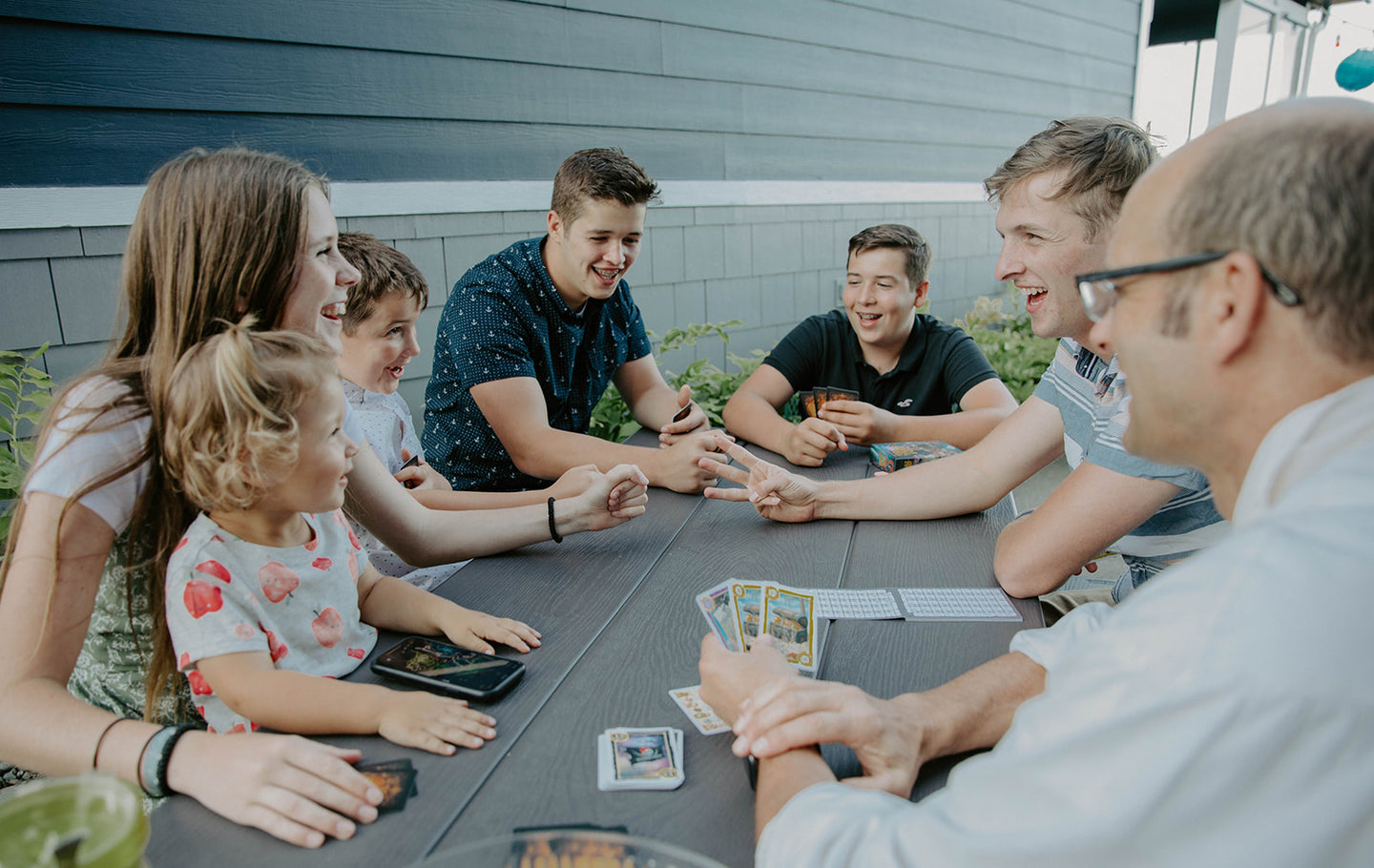 Landscape Photo of Family Playing a Game of Cards from Grandpa Beck's Games on a Grey Table